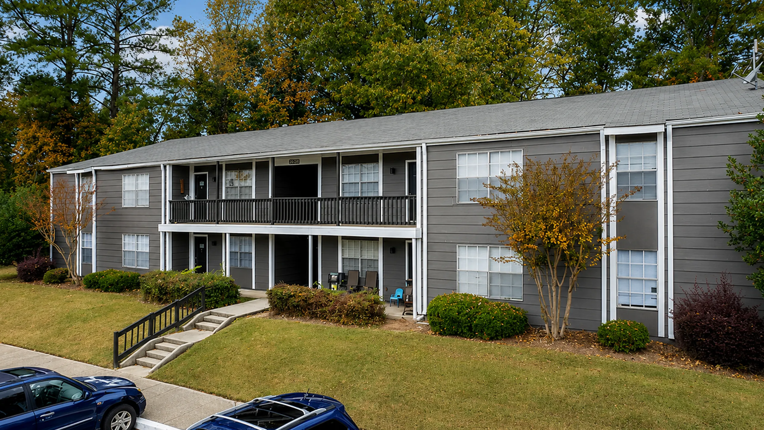 Charming apartment building in a serene wooded setting, featuring inviting front porches and well-maintained landscaping.