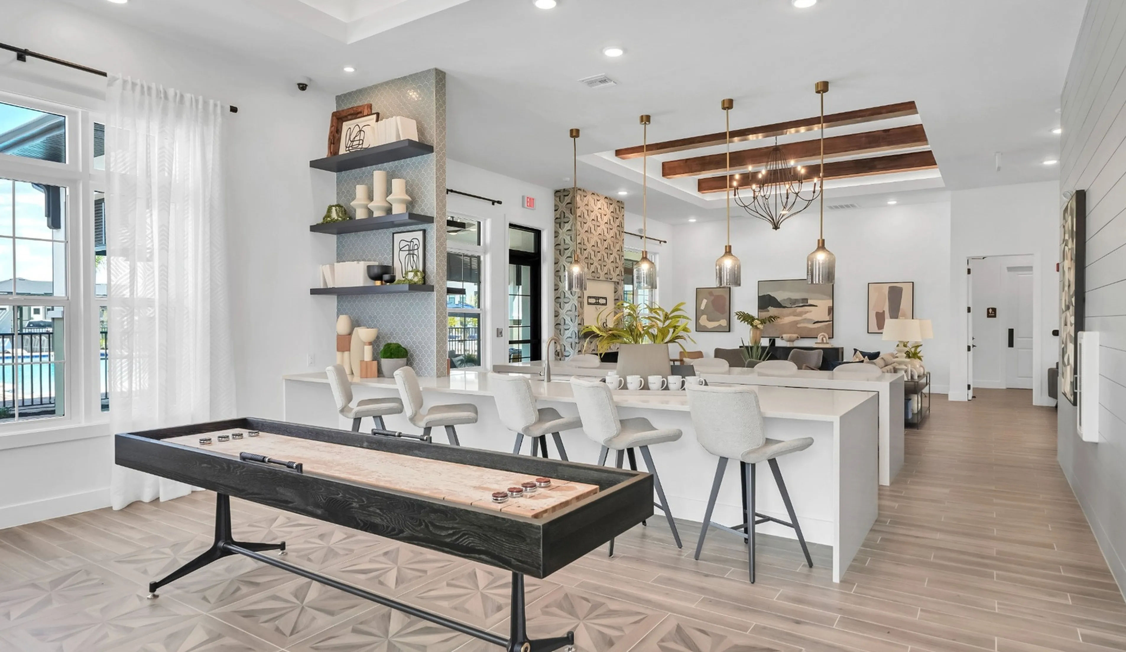 Luxurious open-concept living area with modern decor, featuring a chic kitchen island, elegant lighting, and a shuffleboard table for entertainment.