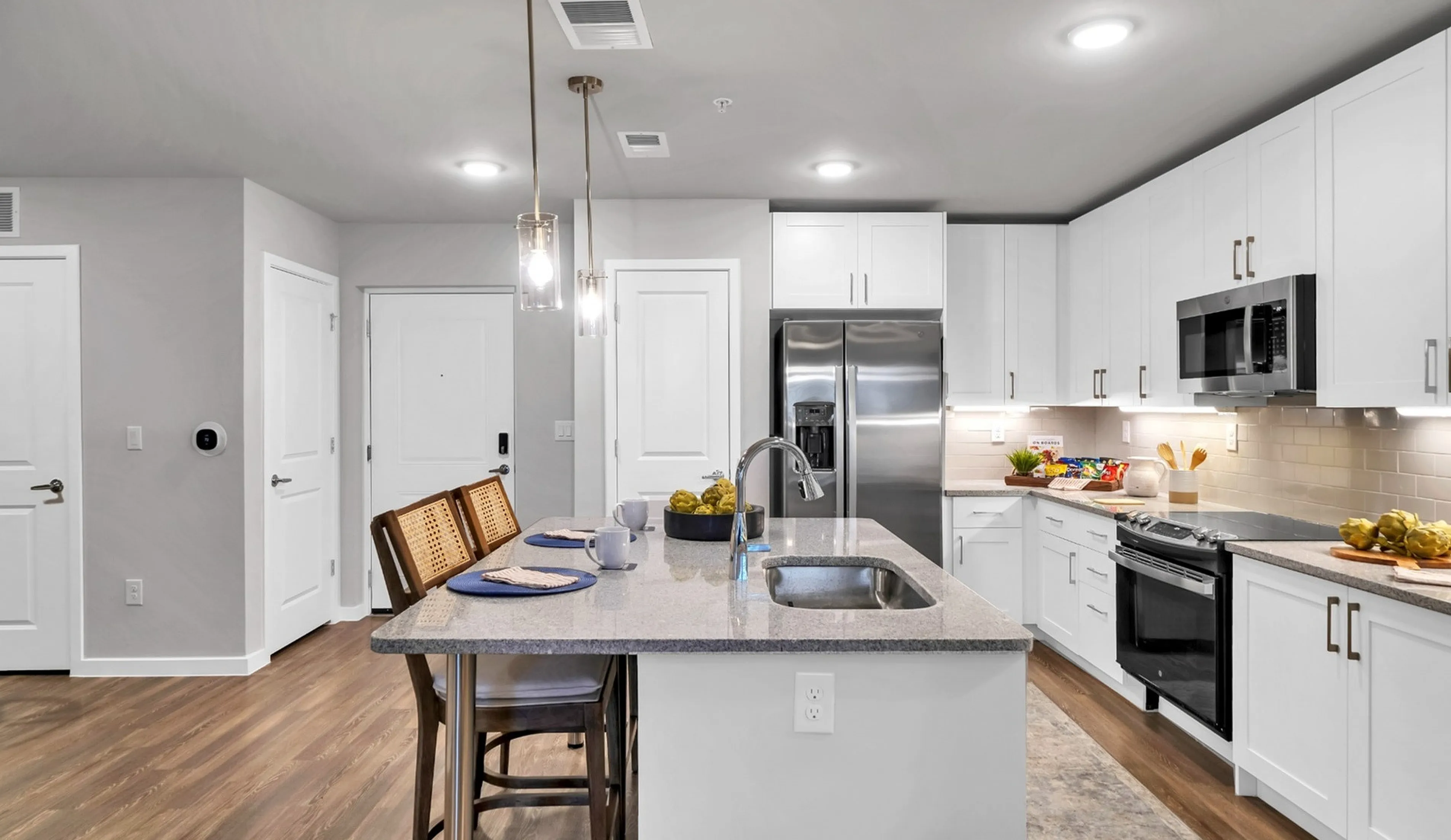 Modern kitchen with sleek countertops, stylish island, and stainless steel appliances in a bright open space.