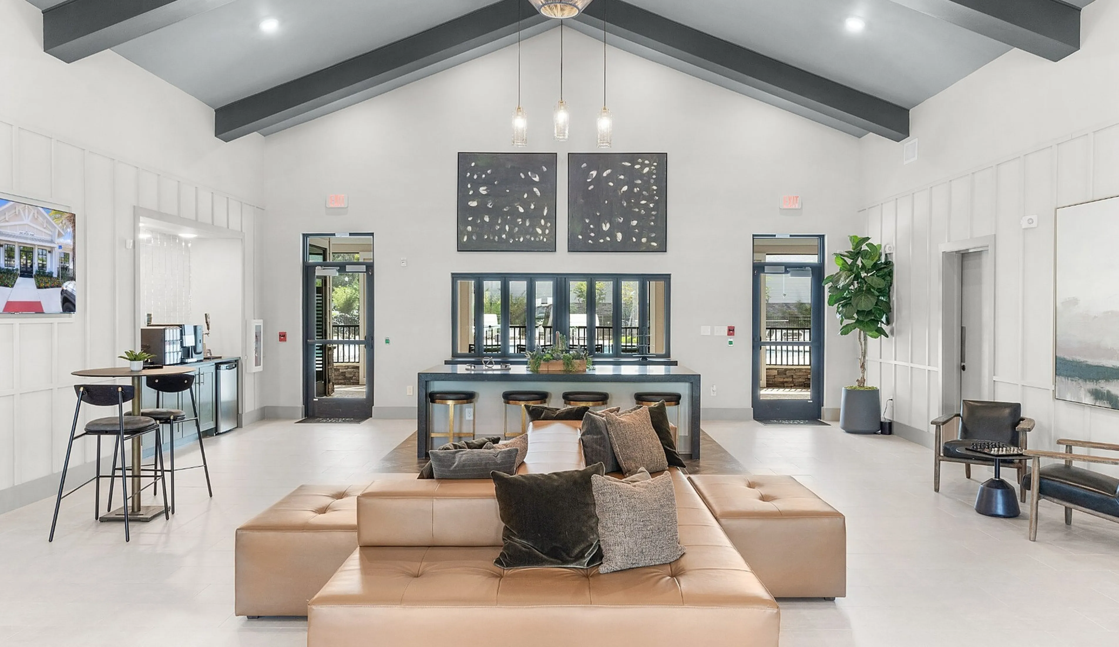 Modern and inviting communal lounge featuring plush seating, sleek bar area with stools, and elegant decor under vaulted ceilings.