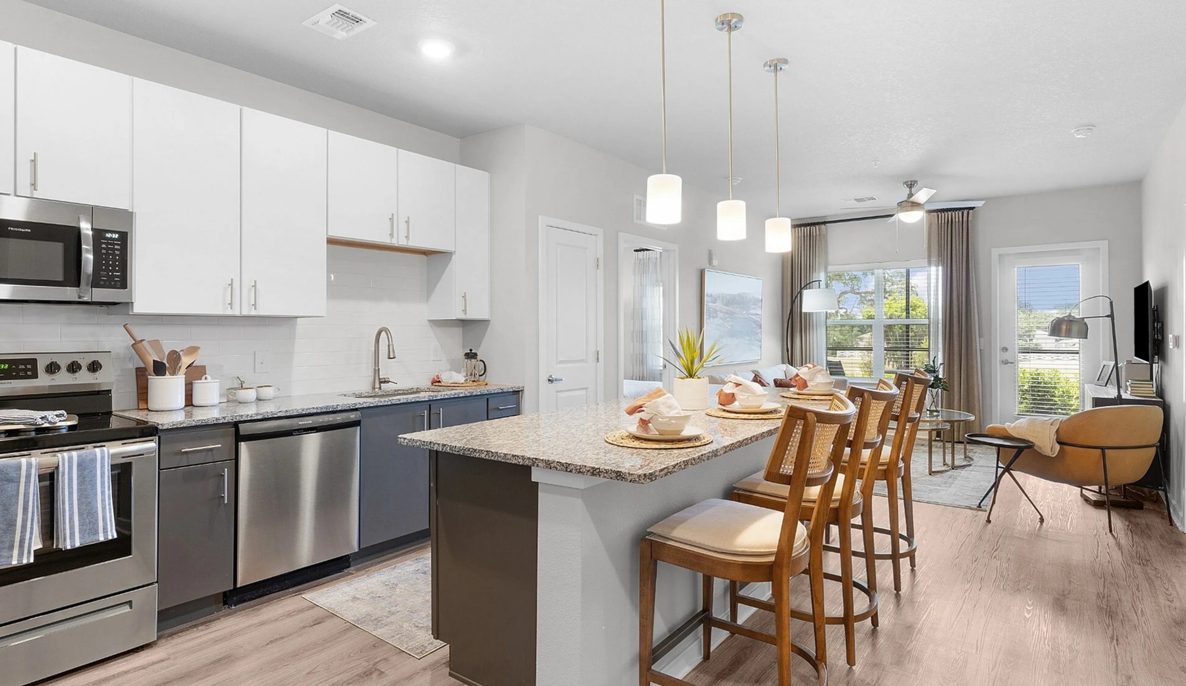 Modern open-concept kitchen and living room with stylish granite countertops, sleek appliances, and ample natural light, perfect for entertaining.