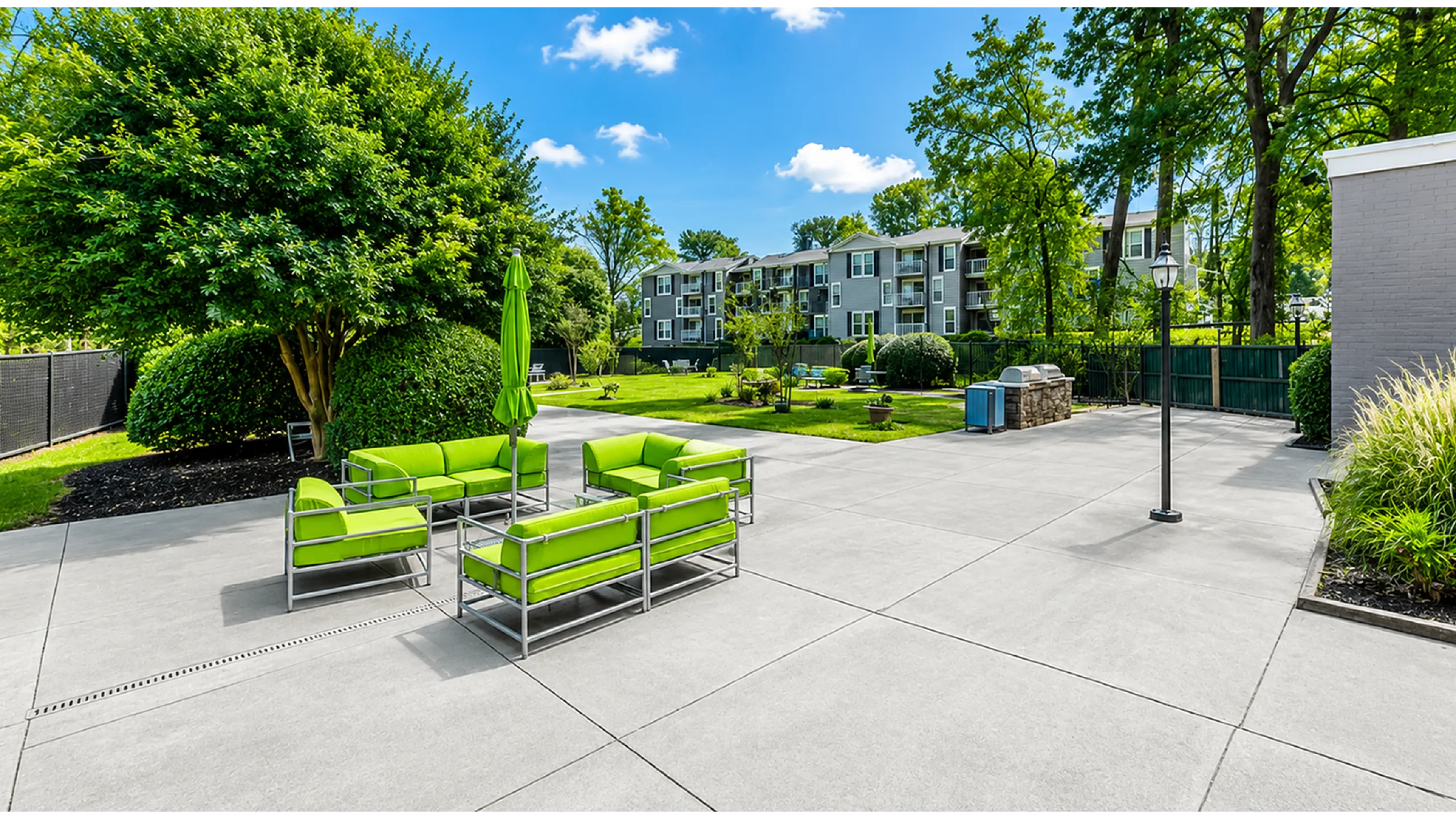 Inviting outdoor patio area with vibrant green seating, surrounded by lush greenery and modern apartment buildings, perfect for relaxation and social gatherings.