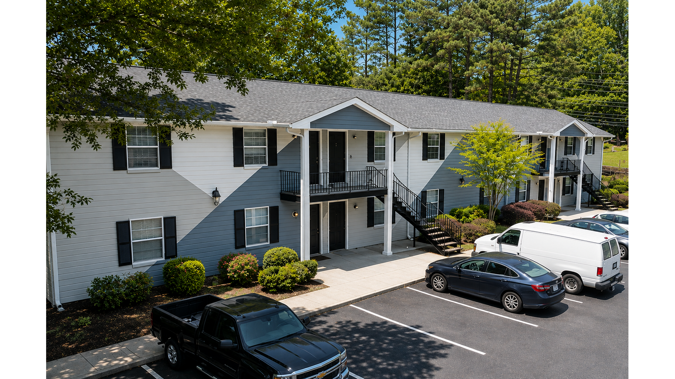 Charming two-story apartment complex with elegant exterior, lush greenery, and convenient parking in a serene setting.