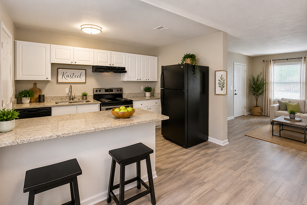 Modern kitchen and cozy living area with gleaming countertops, black appliances, and warm wood flooring, infused with natural light and greenery.