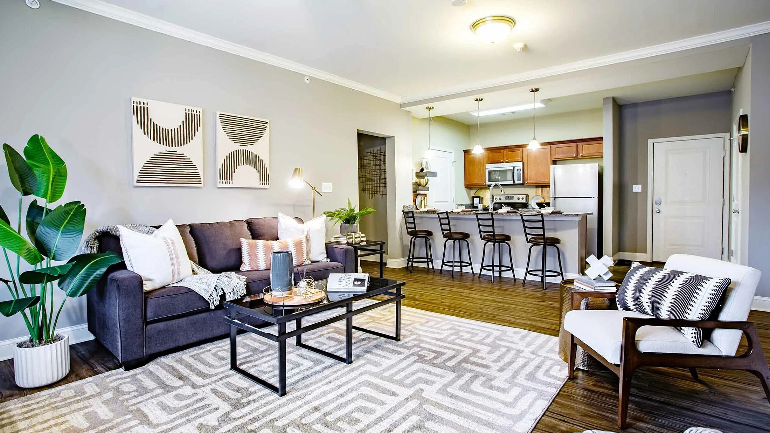 Stylish open-concept living room with modern decor, plush seating, and a sleek kitchen bar area.