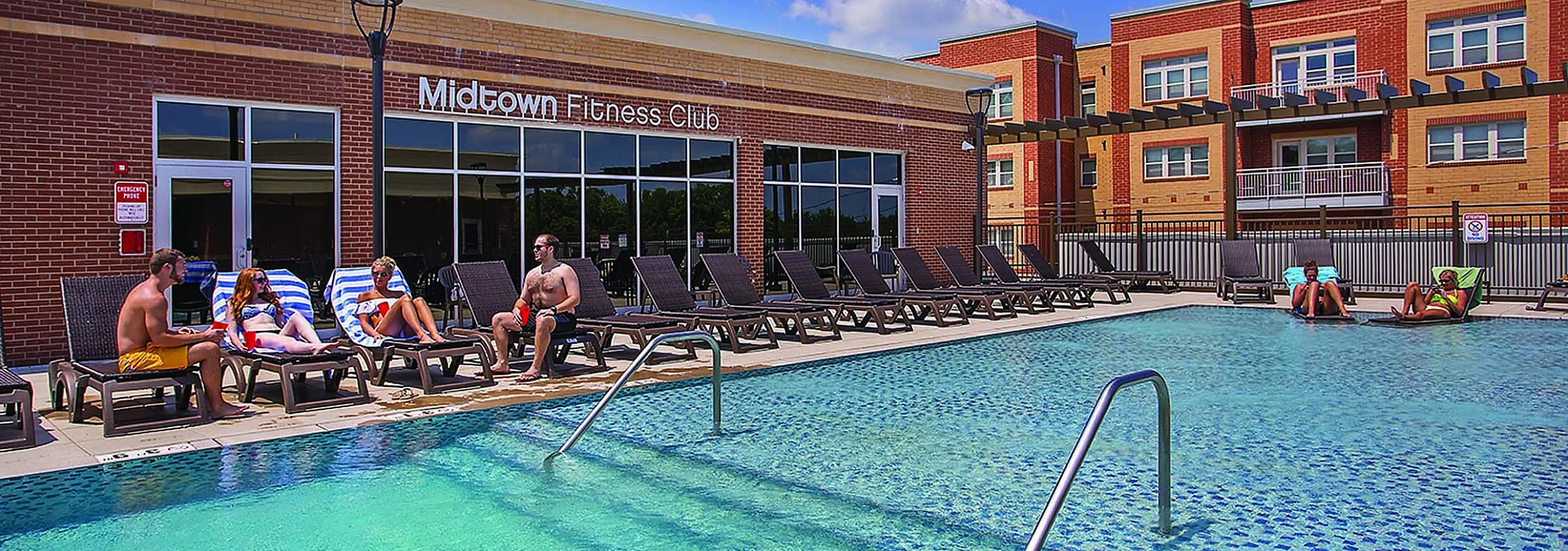 Chic outdoor pool with sun loungers and a modern fitness club at Midtown Apartments.