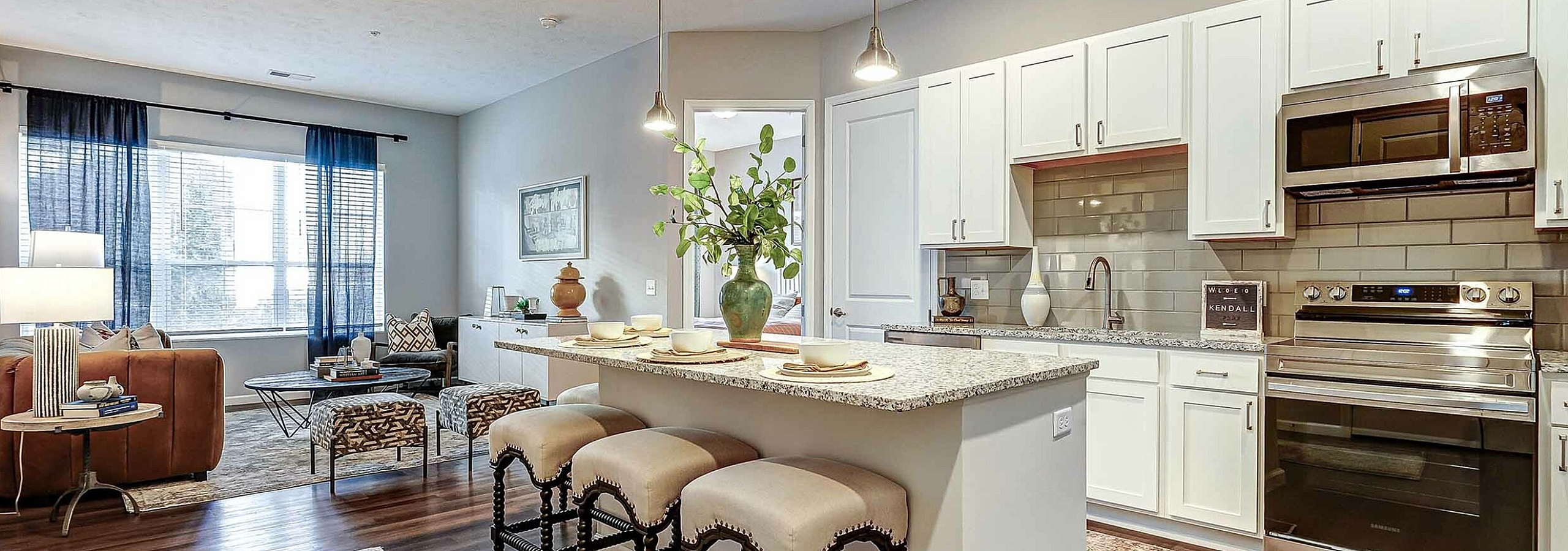 Chic open-concept kitchen and living area with stylish granite countertops, inviting bar seating, and elegant lighting in a modern apartment.