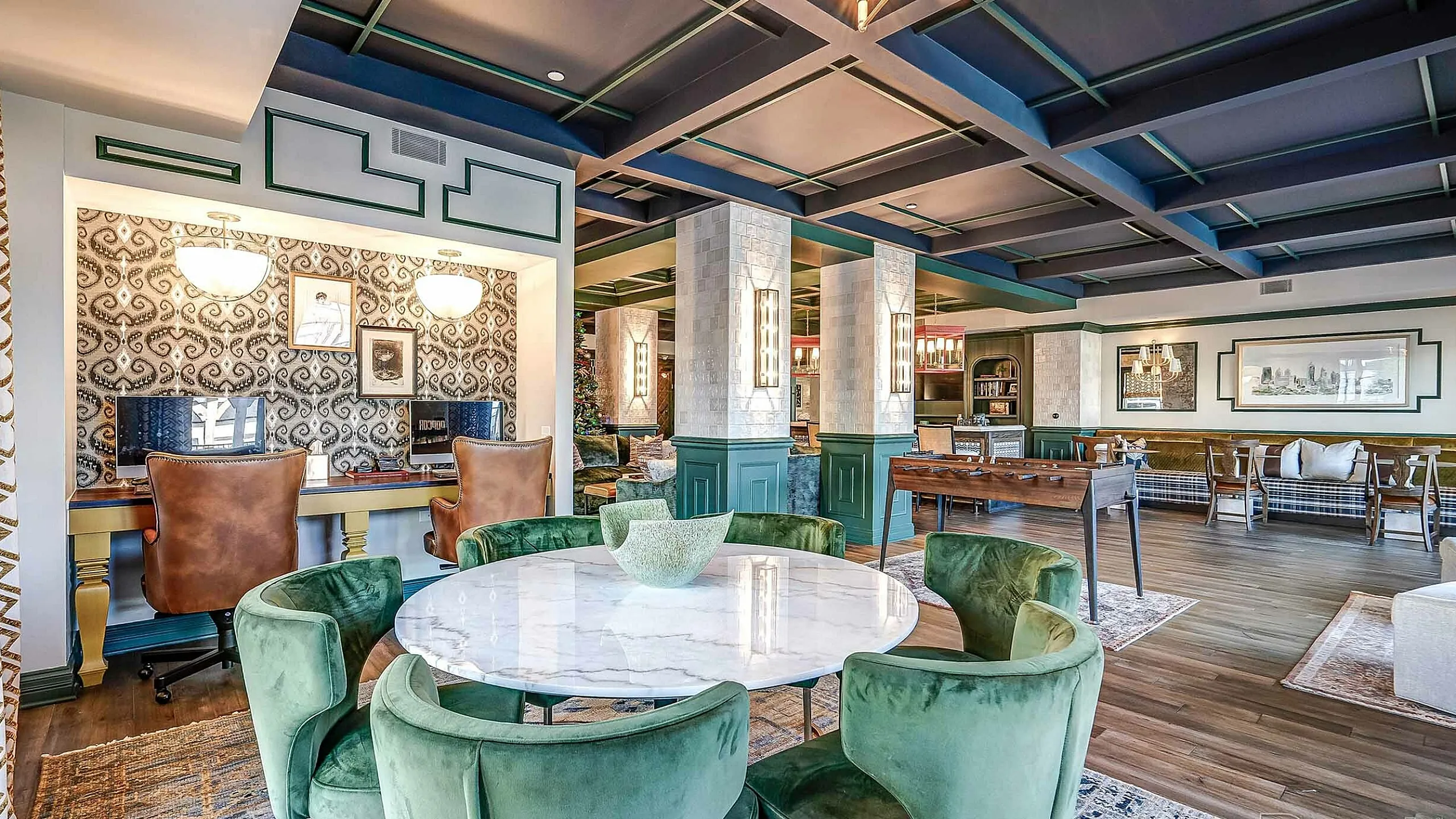 Elegant and inviting communal space featuring luxurious green velvet chairs, a chic marble table, and a stylish lounge area with sophisticated decor.