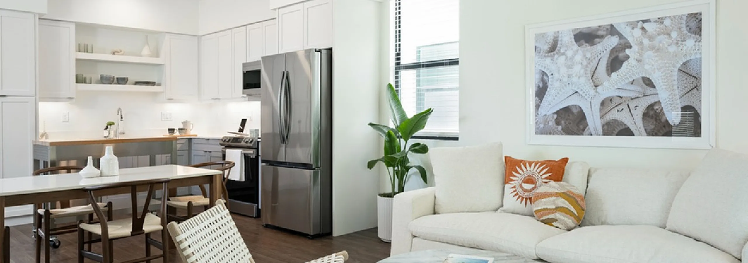 Elegant open-concept living area showcasing modern kitchen with stainless steel appliances, cozy seating, and stylish decor.