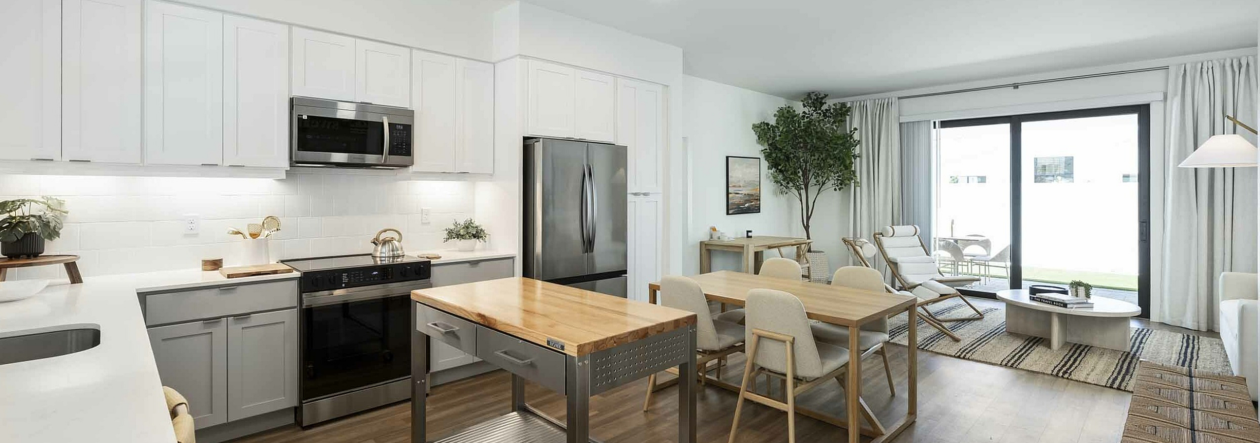 Bright open-concept kitchen and living area with modern appliances, elegant dining setup, and expansive sliding doors leading to a cozy outdoor space.