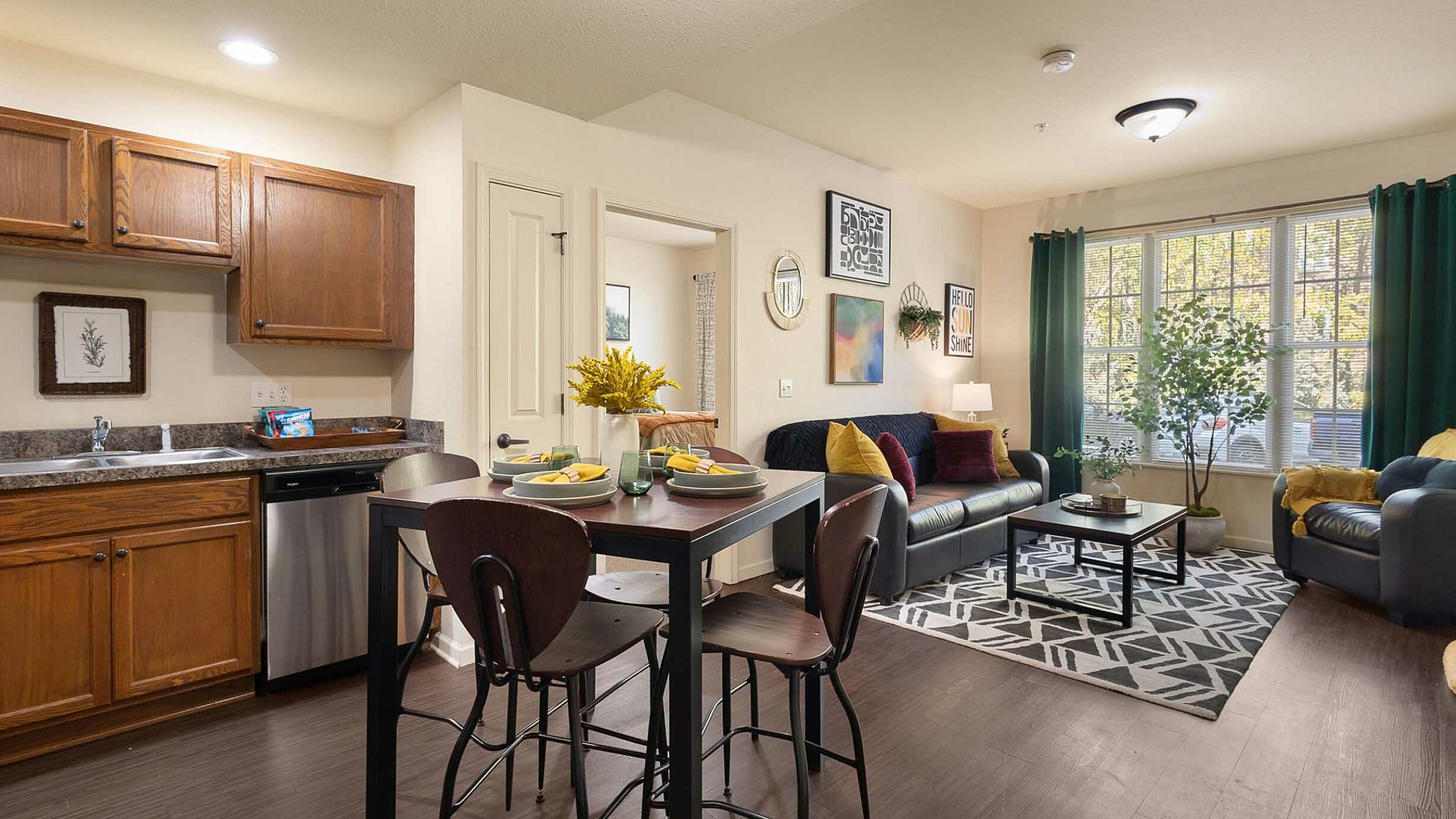 Contemporary open-concept living space with stylish kitchen, cozy dining area, and sunlit living room featuring modern decor and lush greenery.
