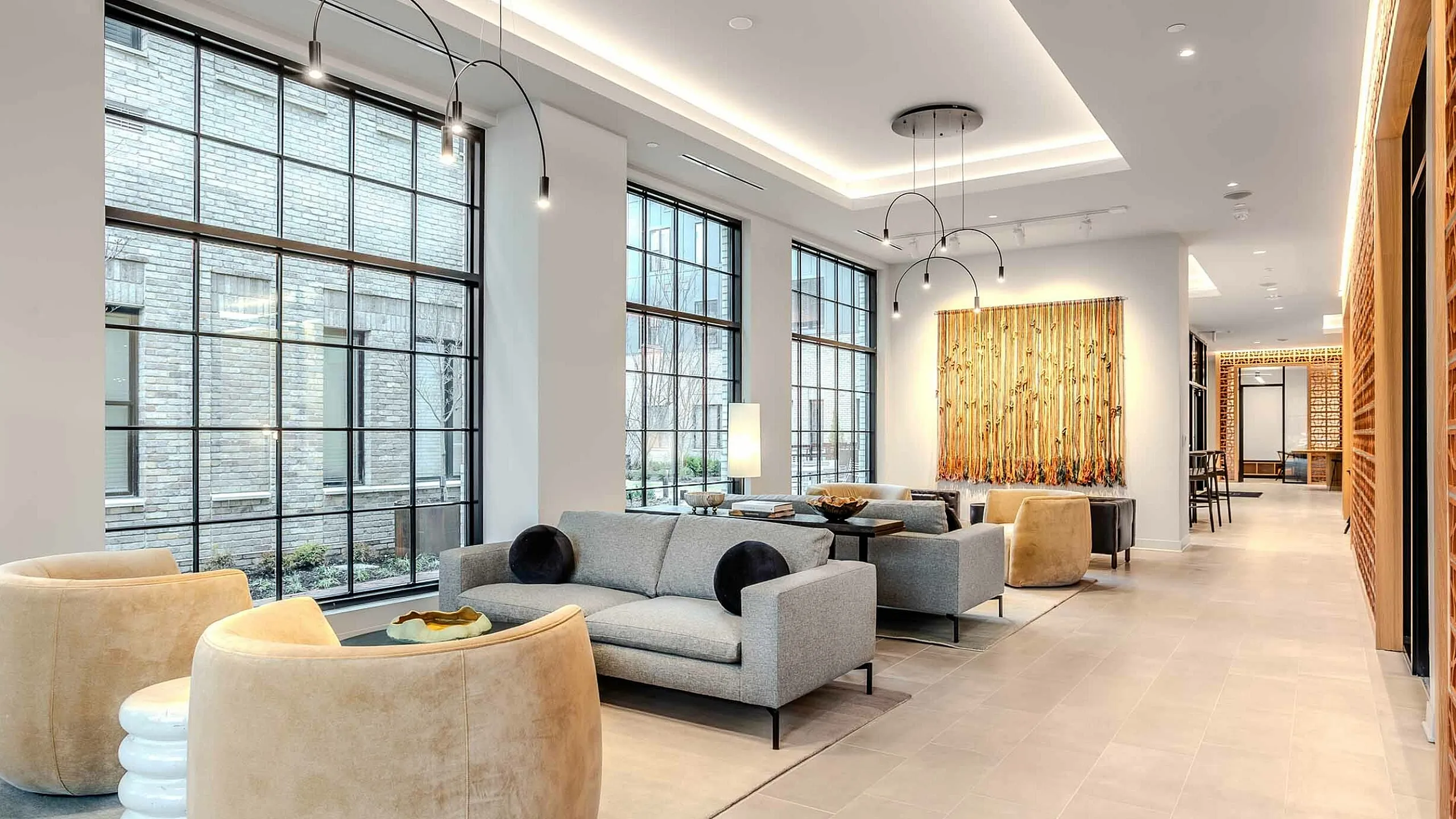 Elegant modern lounge with large windows, stylish sofas, and unique lighting, offering a warm and inviting atmosphere.