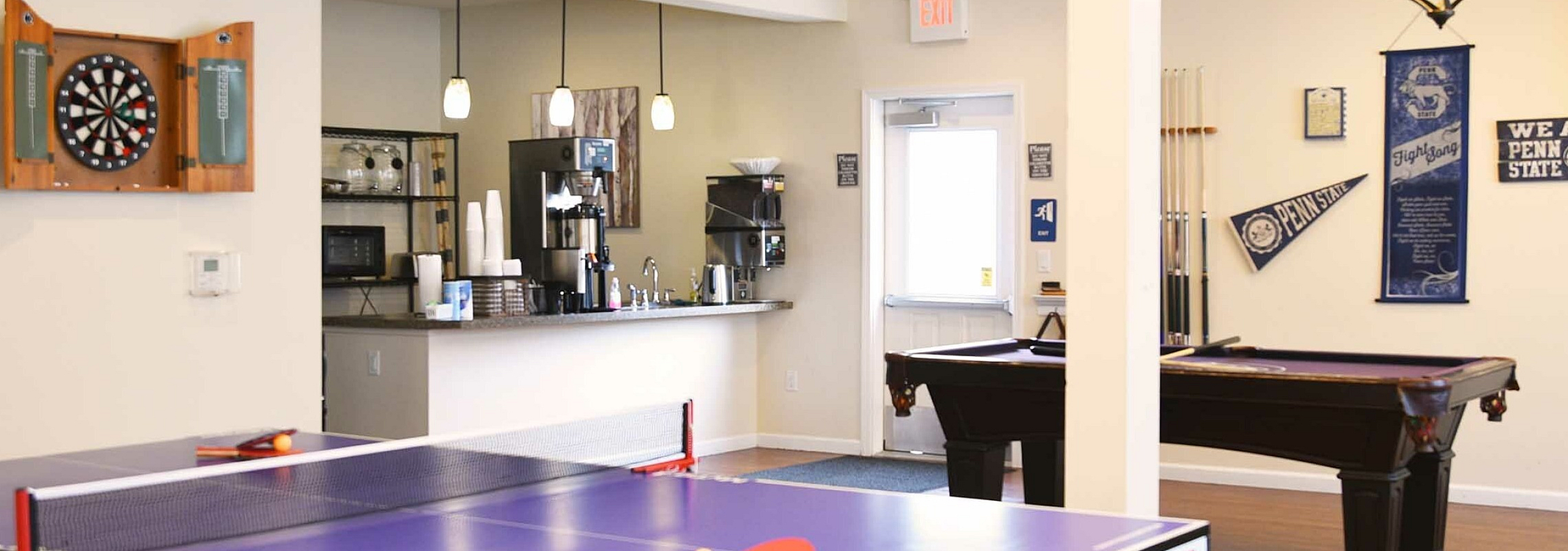 Inviting recreational space featuring a ping pong table, dartboard, and cozy coffee bar with stylish decor.