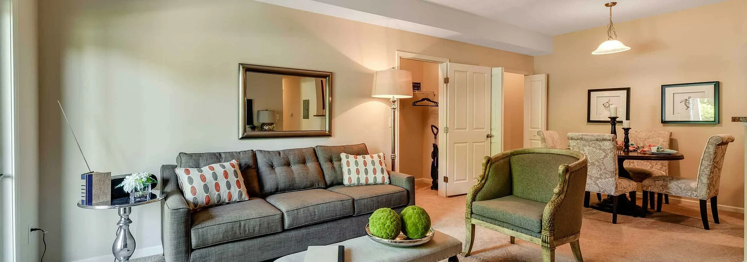 Inviting and stylish living room with a plush gray sofa, elegant coffee table, and charming dining area in an open-concept apartment, perfect for comfort and entertaining.
