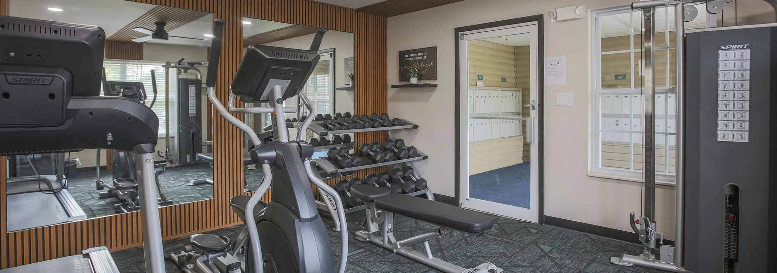 Modern fitness room with state-of-the-art gym equipment, including elliptical, treadmill, and a complete set of weights, ideal for an active lifestyle.