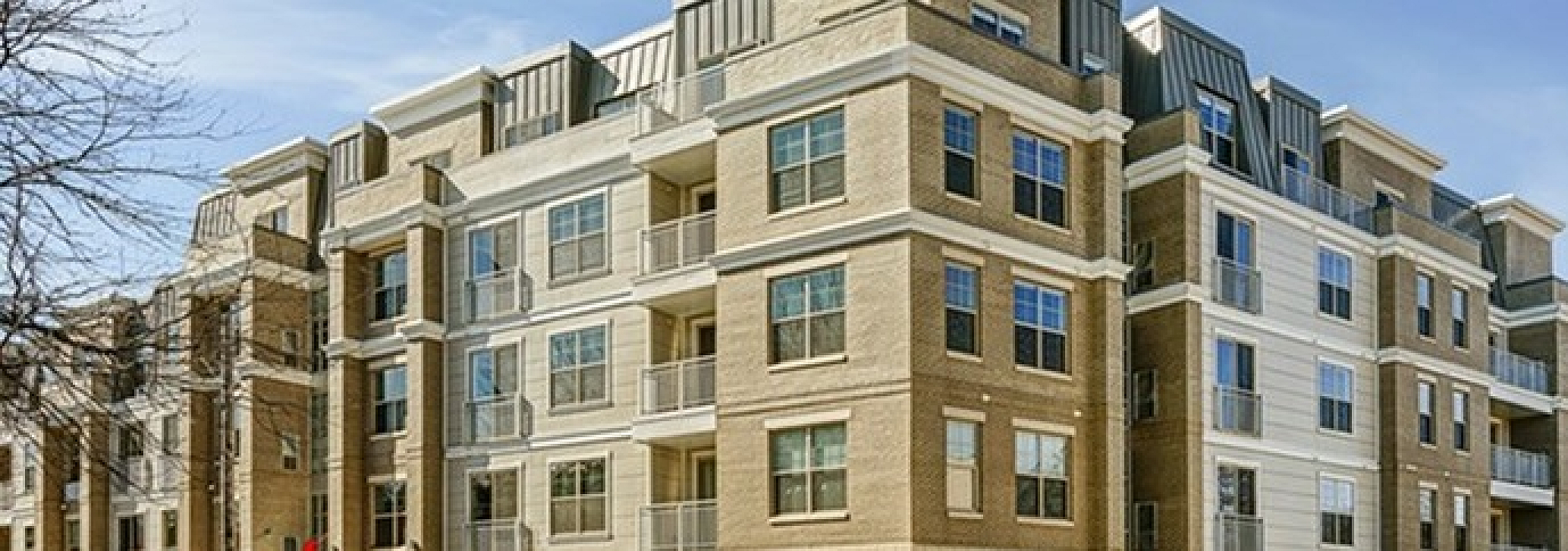 Modern multi-story apartment building with spacious balconies, elegant brickwork, and a vibrant urban setting.