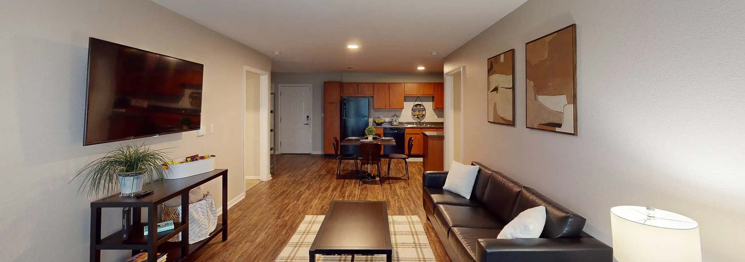 Inviting open-concept living room with sleek modern decor, comfortable seating, and a view into a contemporary kitchen, featuring warm wood tones and elegant design.