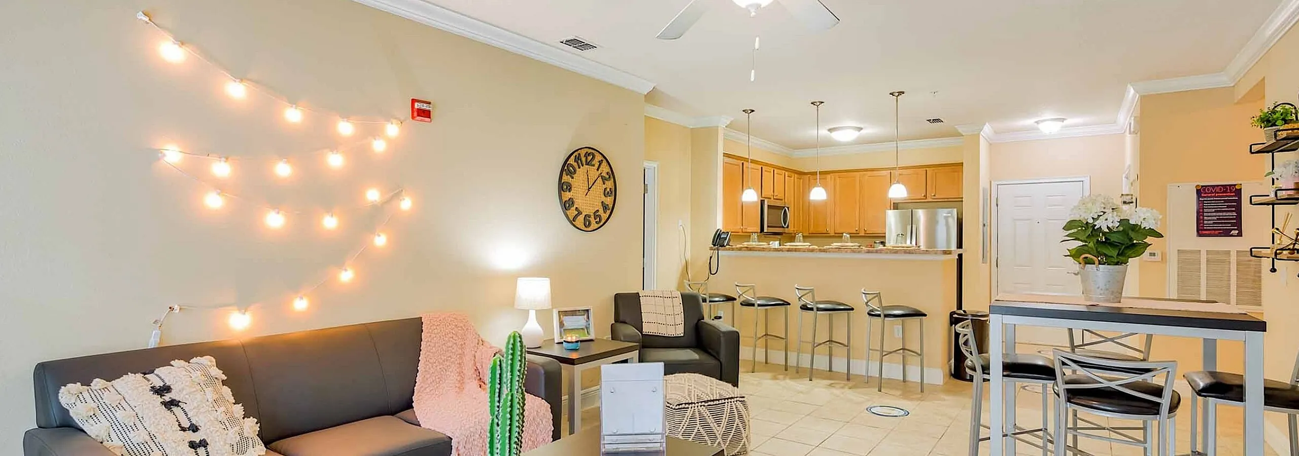 Inviting open-concept living area with modern furniture, ambient string lights, and a sleek kitchen bar in a stylish apartment.