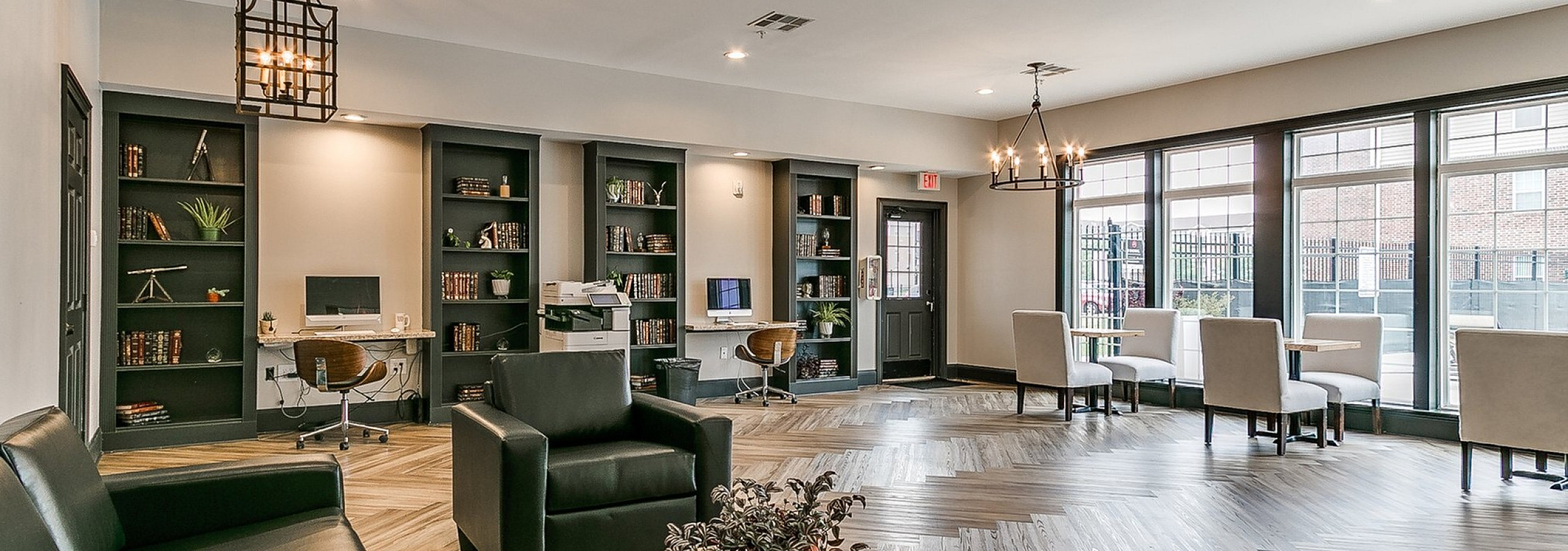 Elegant communal lounge space with modern leather seating, stylish lighting, and floor-to-ceiling windows overlooking a vibrant urban setting.