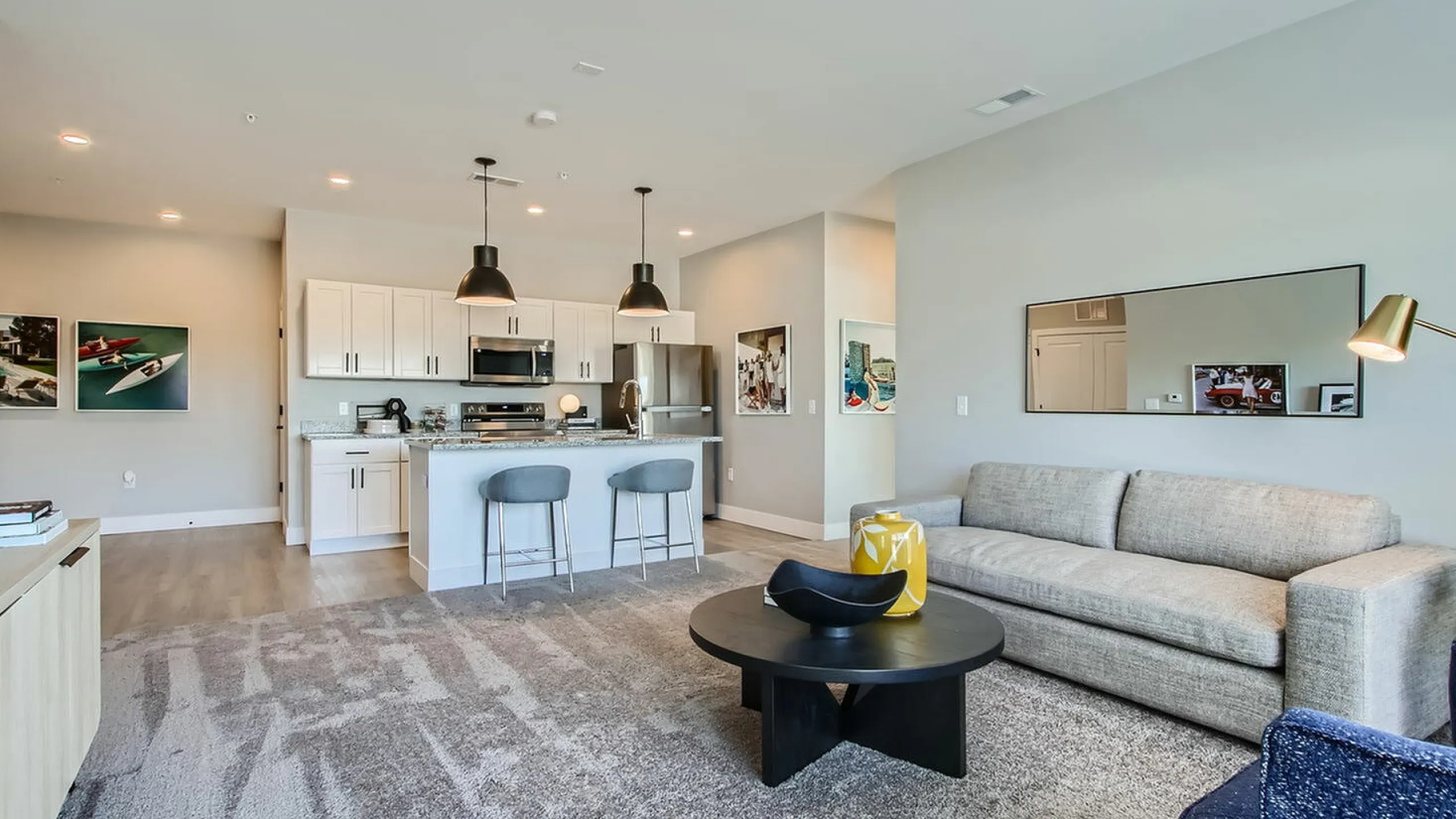 Modern open-plan living room with a sleek kitchen, cozy gray sofa, and stylish decor, offering a spacious, inviting atmosphere.