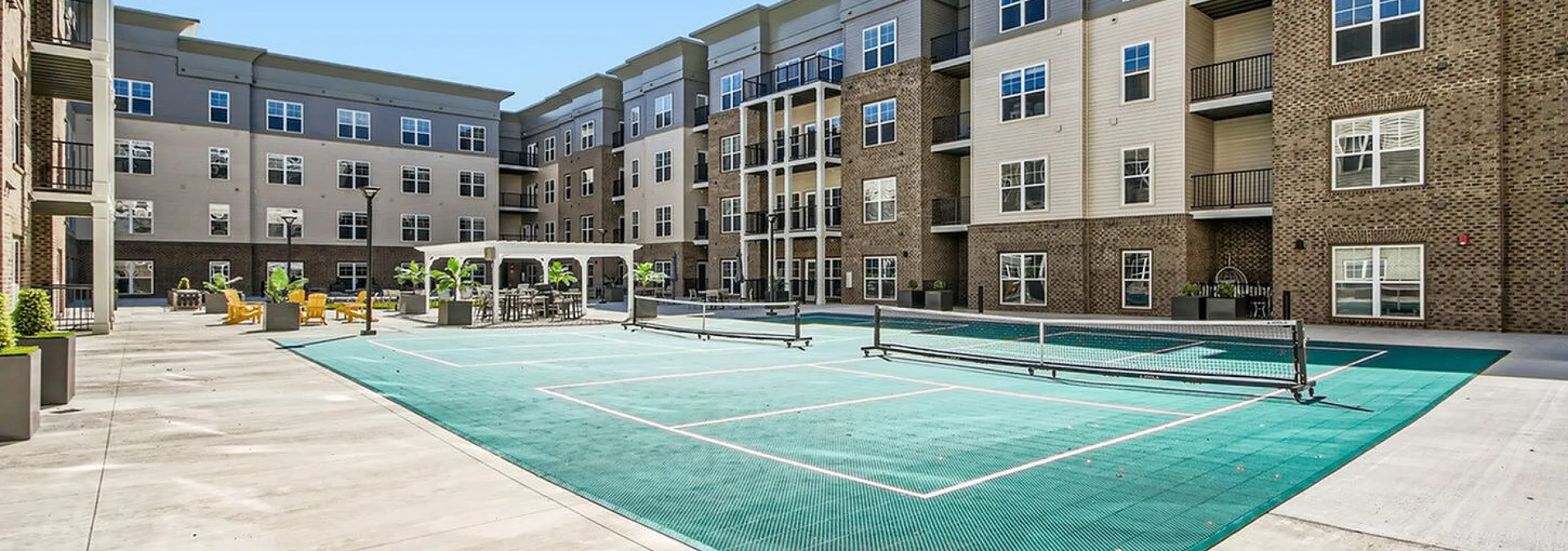 Modern apartment complex featuring an inviting courtyard with a stylish outdoor lounge and a vibrant sports court.