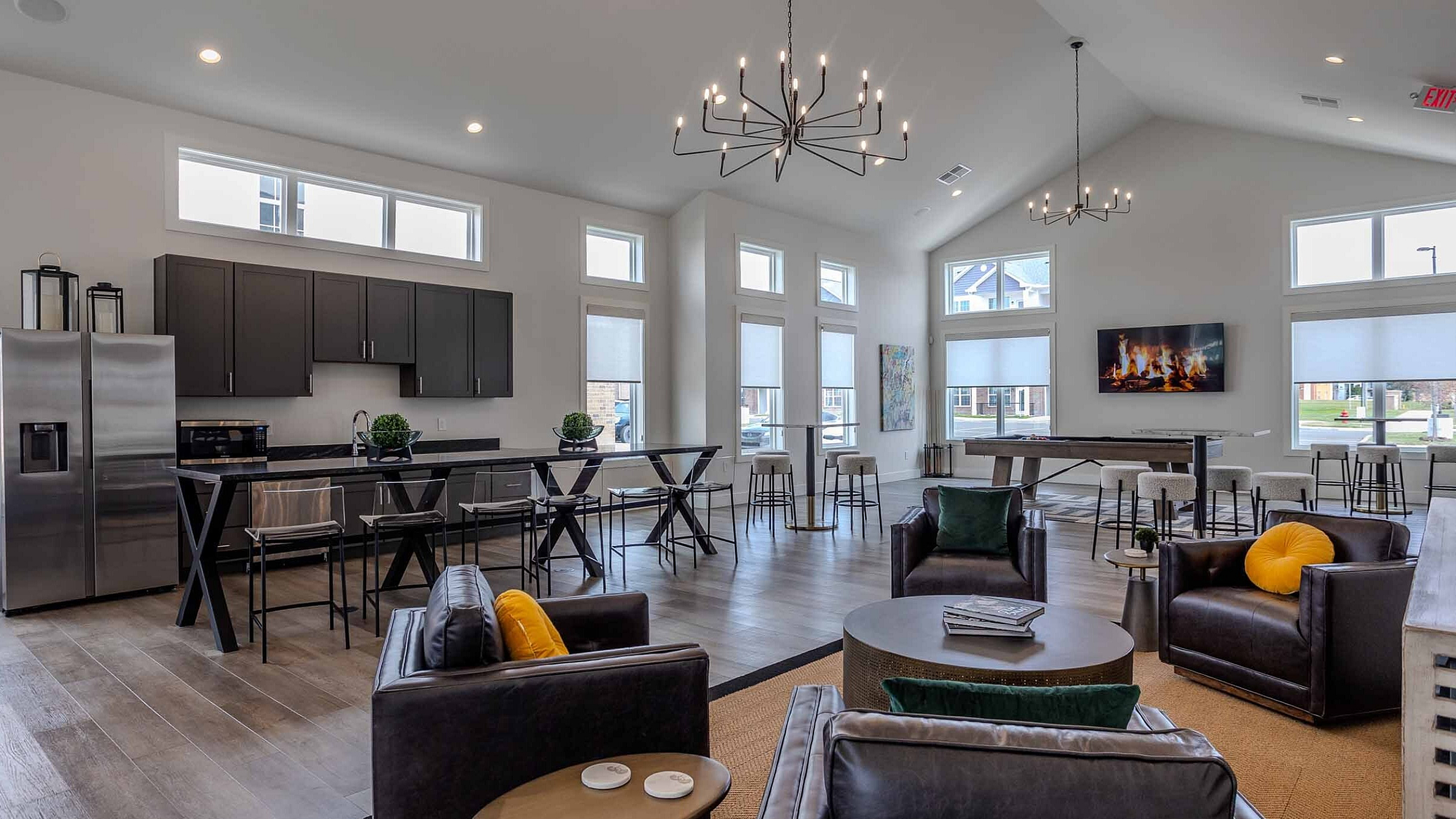 Luxurious open-concept living area with a stylish modern kitchen, elegant chandeliers, and cozy seating by the fireplace.
