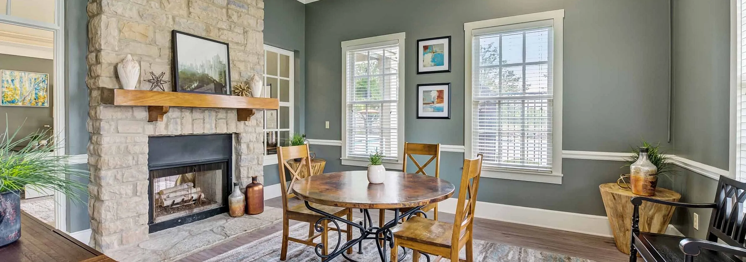 Charming dining area with a rustic stone fireplace, round wooden table, and elegant decor, bathed in natural light.