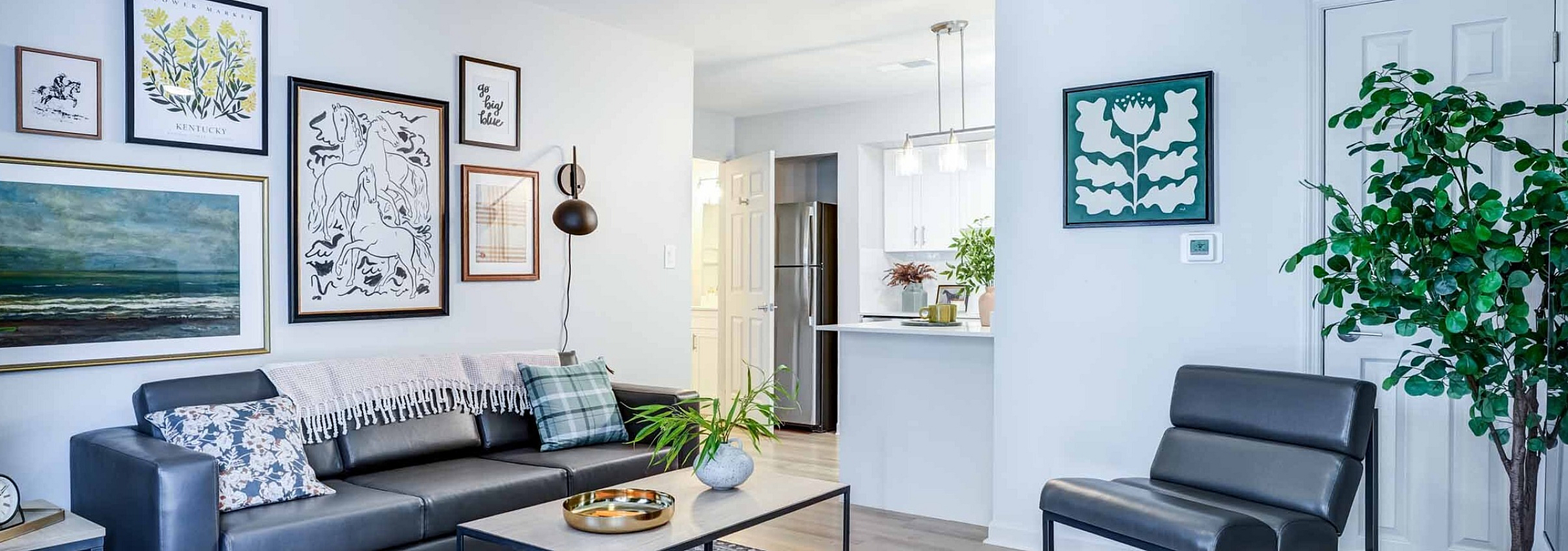 Chic and modern living room with stylish decor, featuring a sleek leather sofa, artistic gallery wall, and an open-concept kitchen perfect for entertaining.