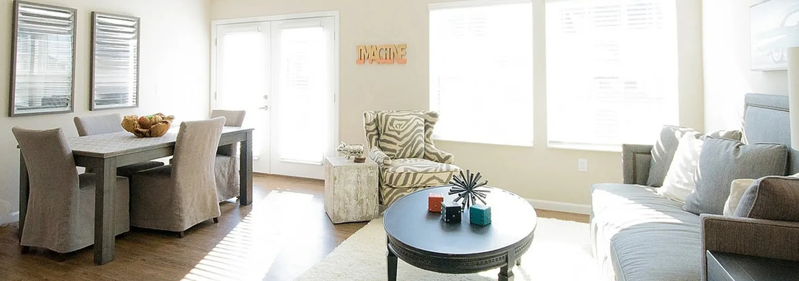 Bright and welcoming living room with stylish furniture, large windows, and modern dining area.