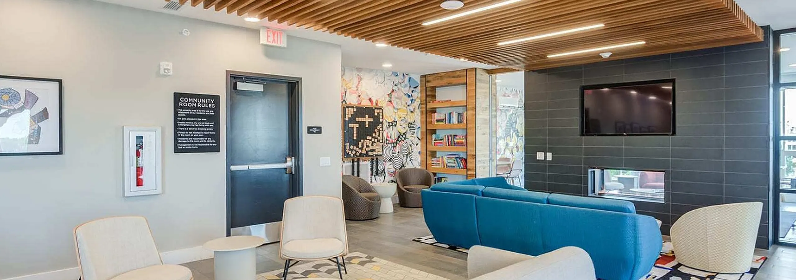 Contemporary community room with stylish seating, vibrant murals, and a modern ceiling design, perfect for relaxation and social gatherings.