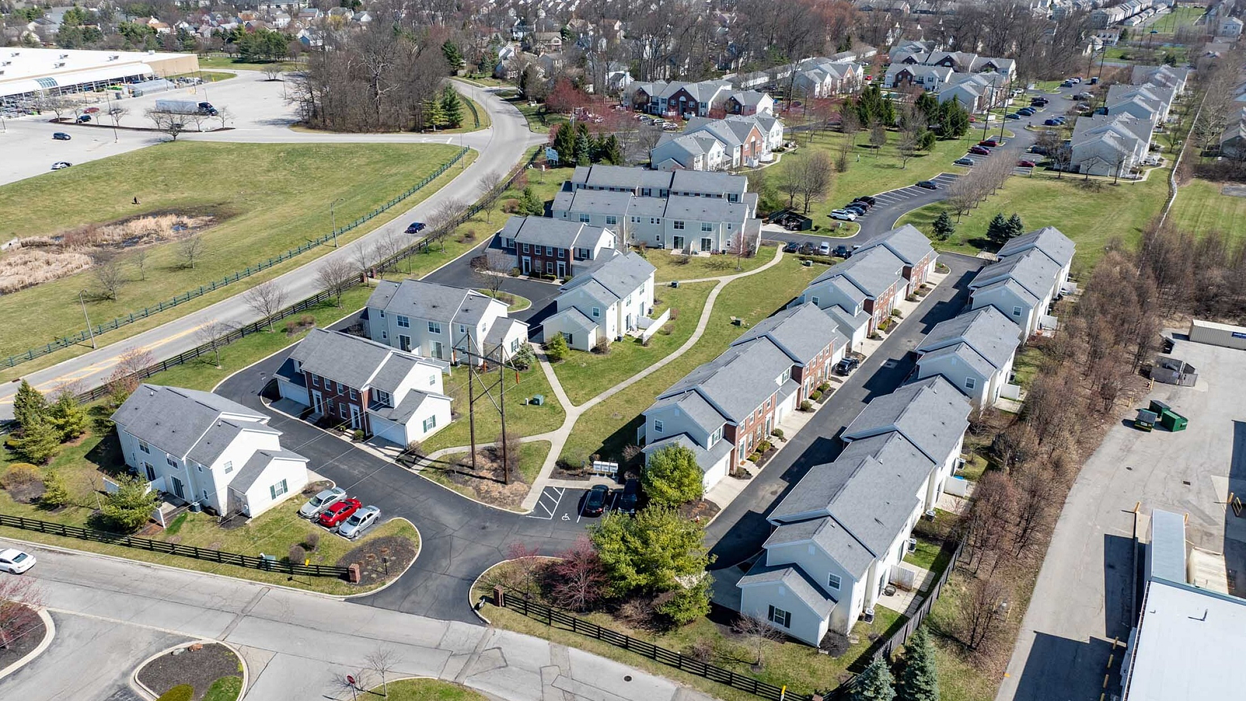 Aerial view of a charming suburban neighborhood featuring modern townhouses with well-maintained lawns and tree-lined streets, offering a peaceful and family-friendly living environment.