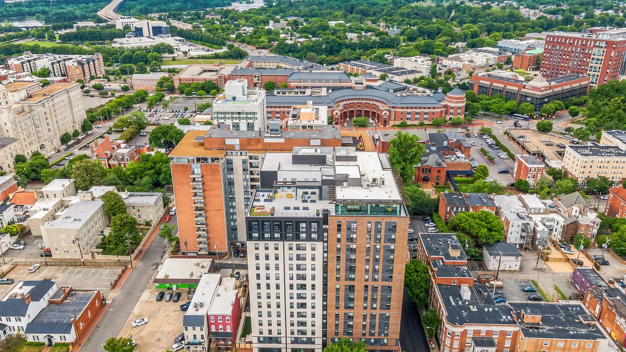 Vibrant urban skyline featuring modern high-rise apartments surrounded by lush greenery and historic architecture, offering a blend of contemporary living and city charm.