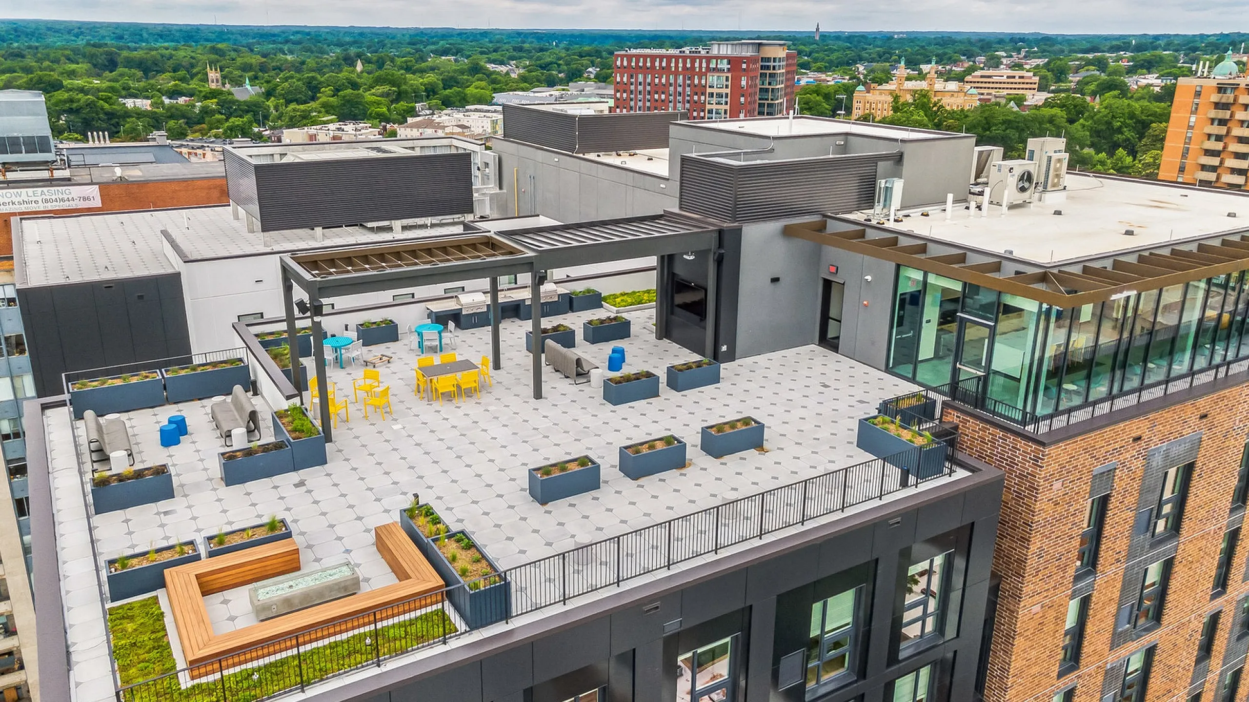 Vibrant rooftop terrace with modern seating and green planters overlooking a scenic cityscape.