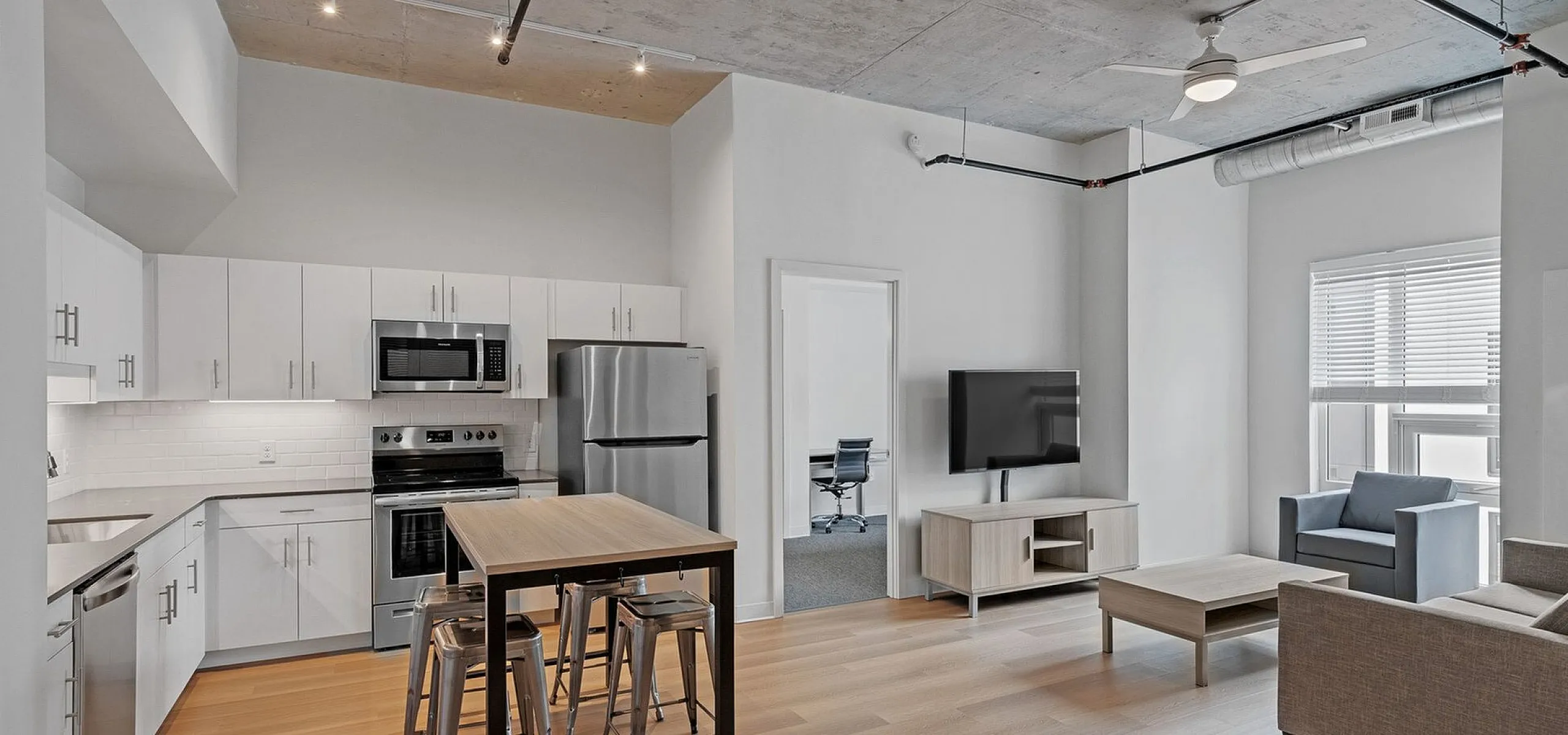 Modern apartment interior with open-concept kitchen and living area, featuring sleek white cabinetry, stainless steel appliances, and inviting natural light.
