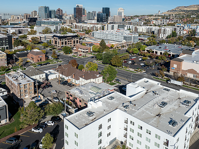 Vibrant aerial view of a bustling urban neighborhood featuring modern apartments, lush greenery, and a stunning city skyline backdrop.