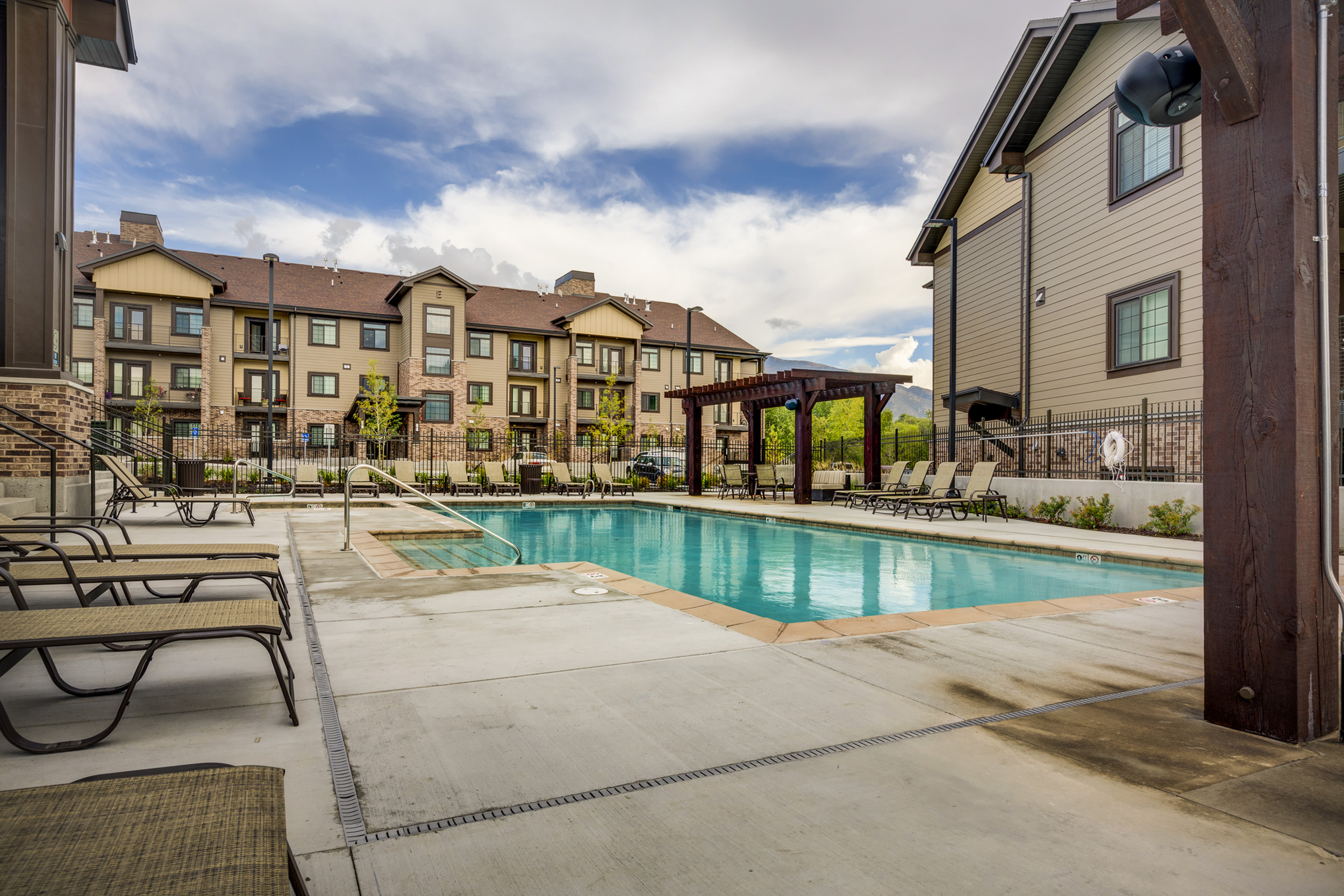 Inviting apartment complex showcasing a luxurious outdoor pool surrounded by modern architecture and scenic greenery.