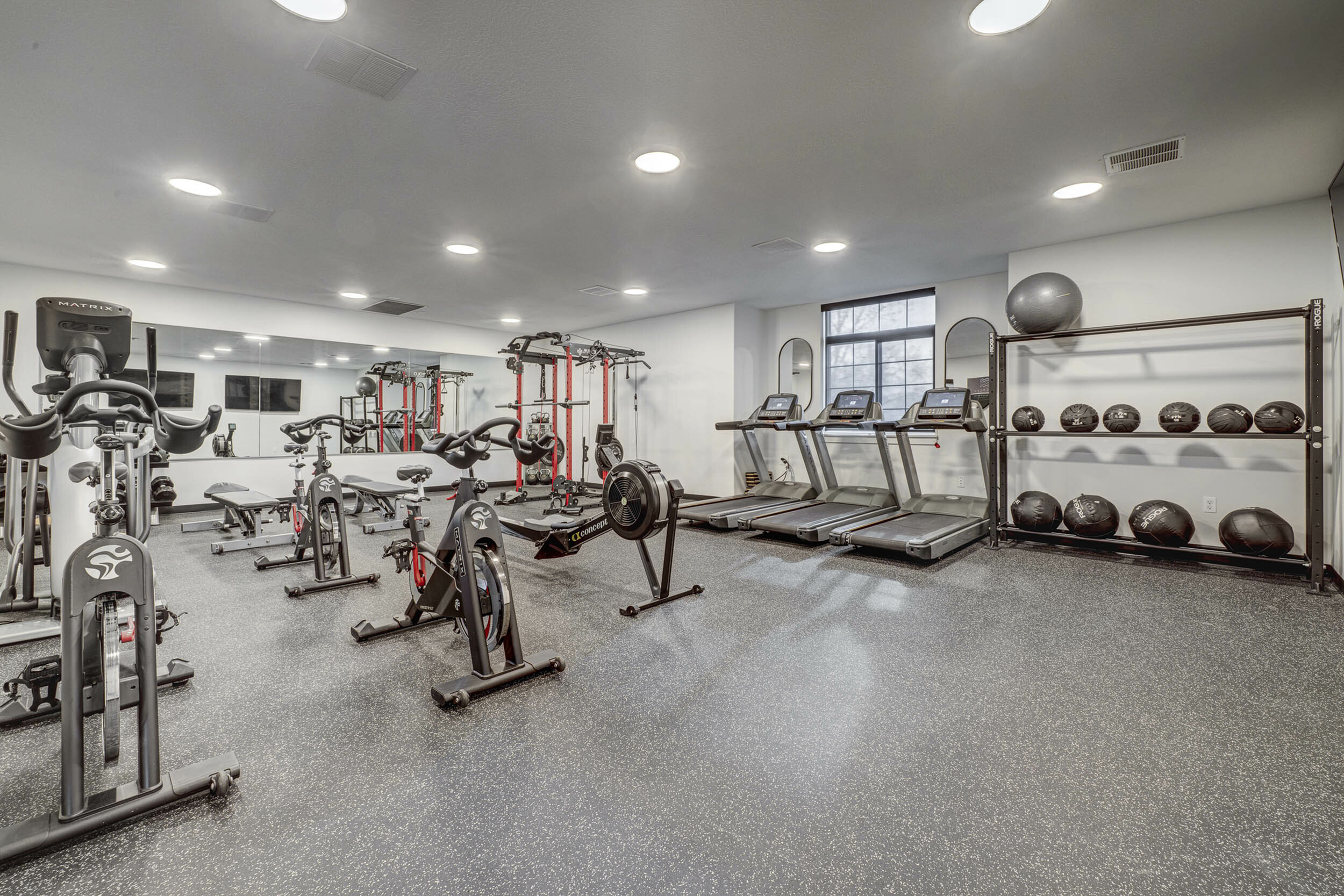 Modern fitness center equipped with state-of-the-art treadmills, stationary bikes, and strength training equipment, featuring ample natural light.