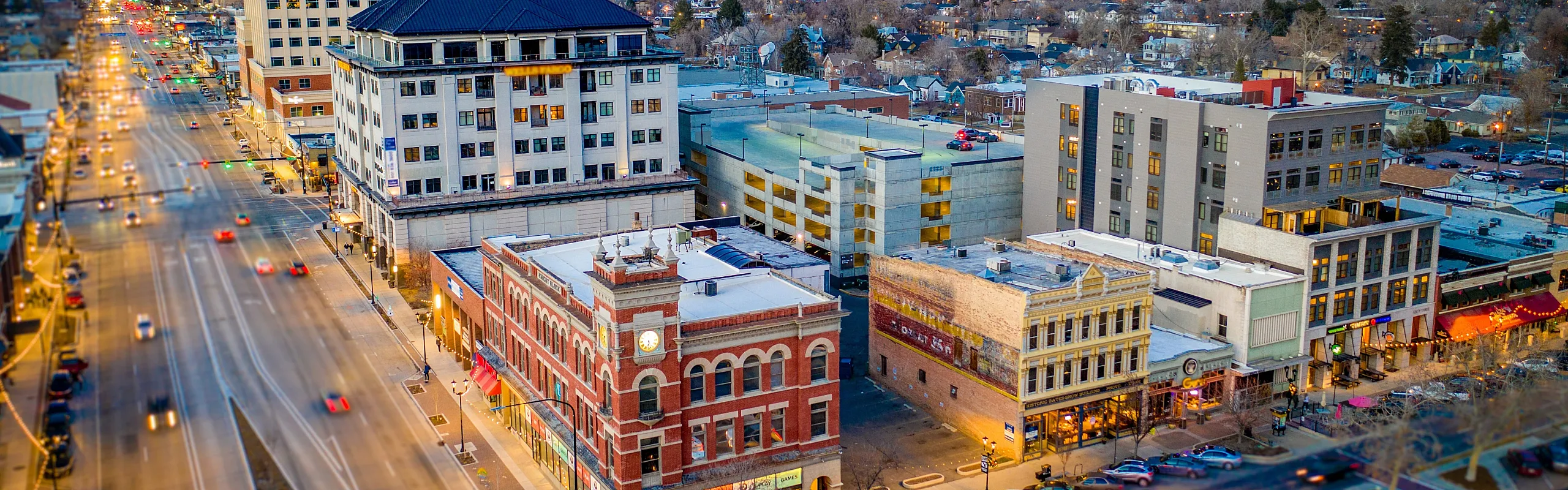 Aerial view of a bustling city street with lit-up historic and modern buildings during twilight.