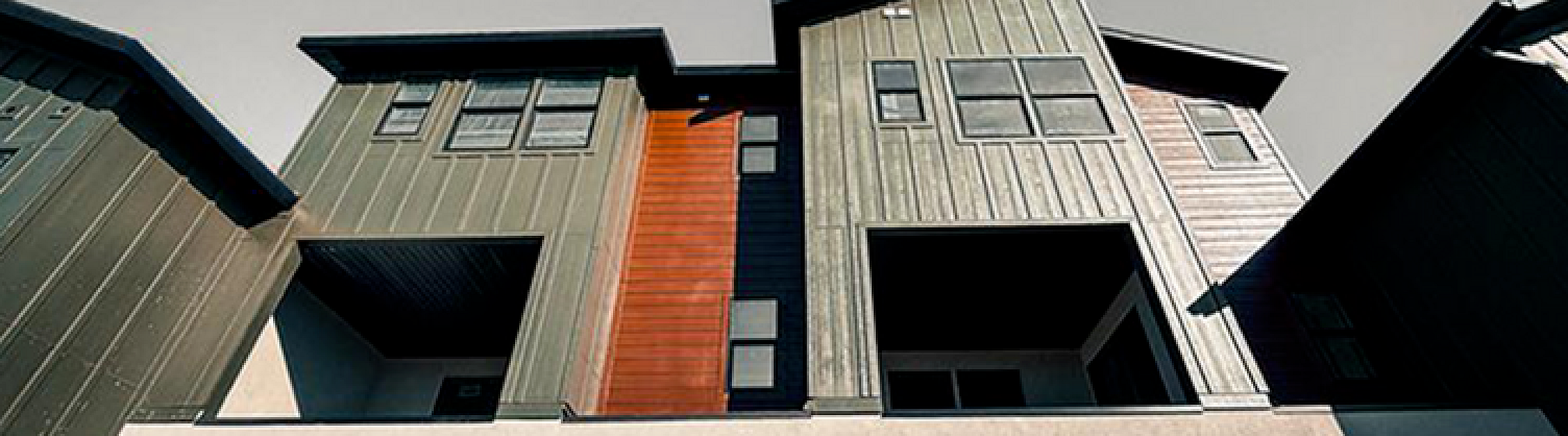 Contemporary townhouse with varied textures and clean lines, featuring large windows and a unique roof design.
