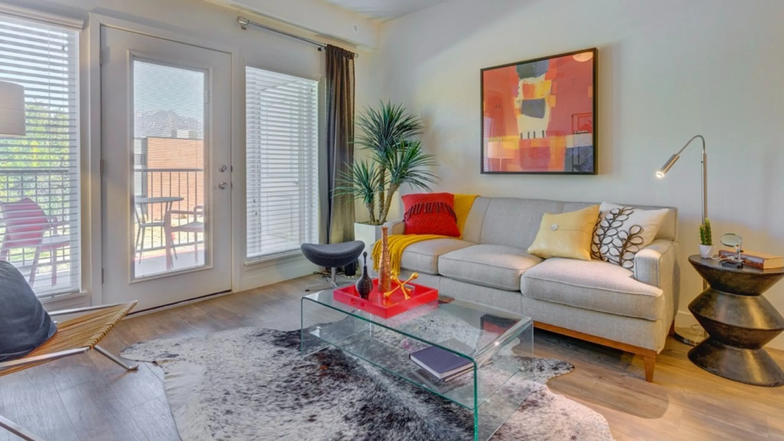 Inviting living room with chic decor, modern sofa, and vibrant artwork, featuring a cozy ambiance and natural light through large windows.