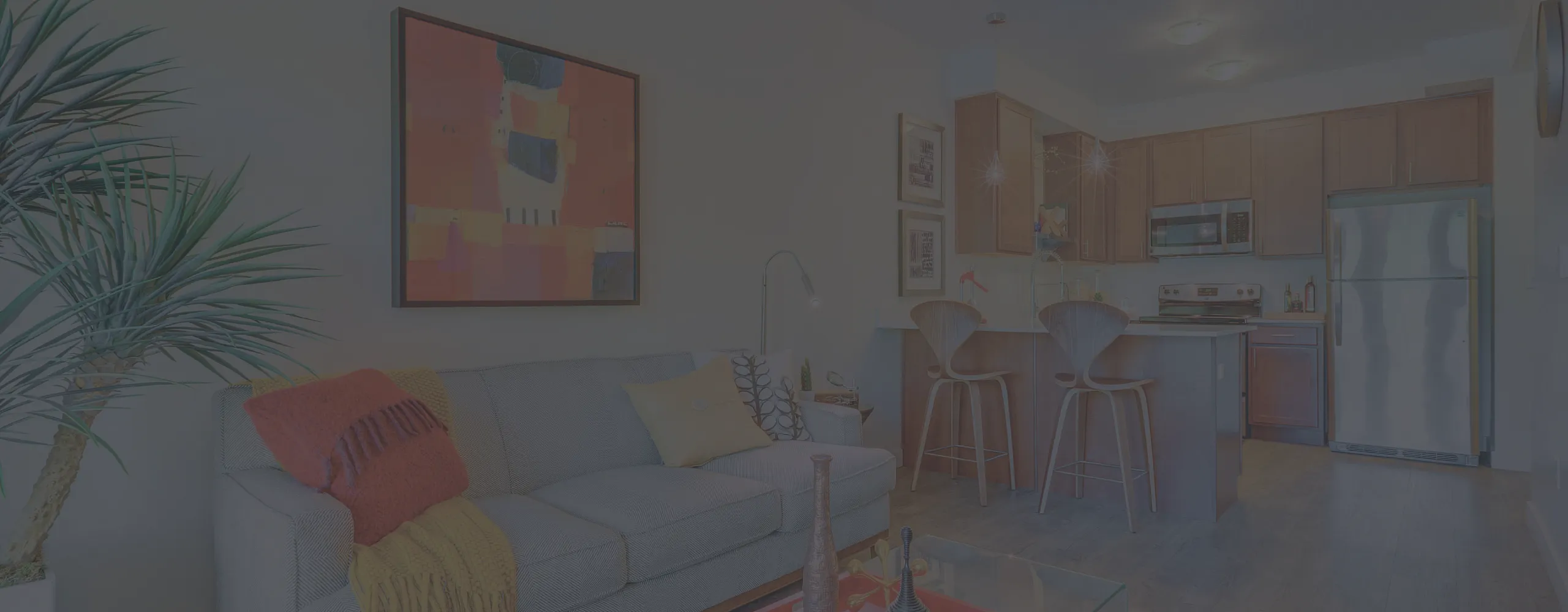 Inviting open-concept living room and kitchen with modern decor, cozy seating, vibrant artwork, and stylish bar stools.