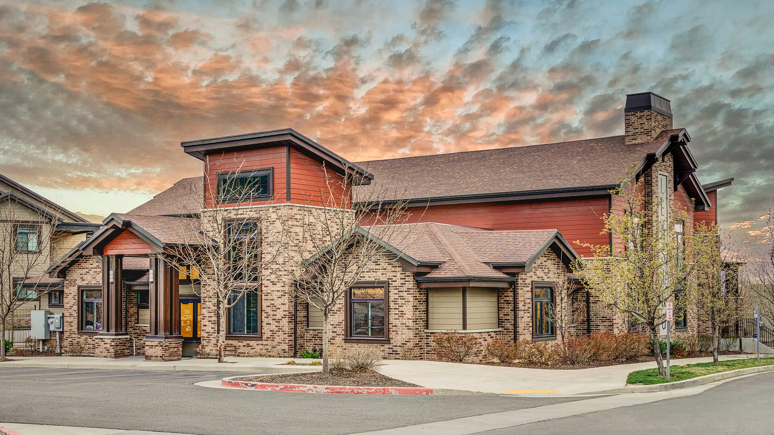 Charming brick apartment complex exterior with modern architectural design, surrounded by a serene landscape under a picturesque sky.