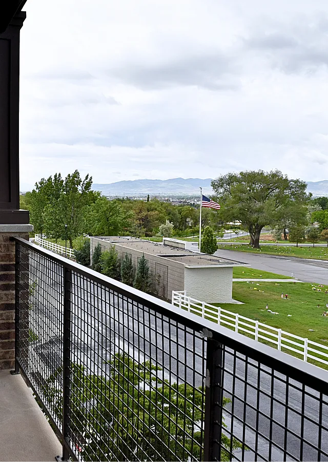 Scenic balcony view showcasing lush greenery, a peaceful neighborhood street, and distant mountains, perfect for relaxation and enjoying nature.