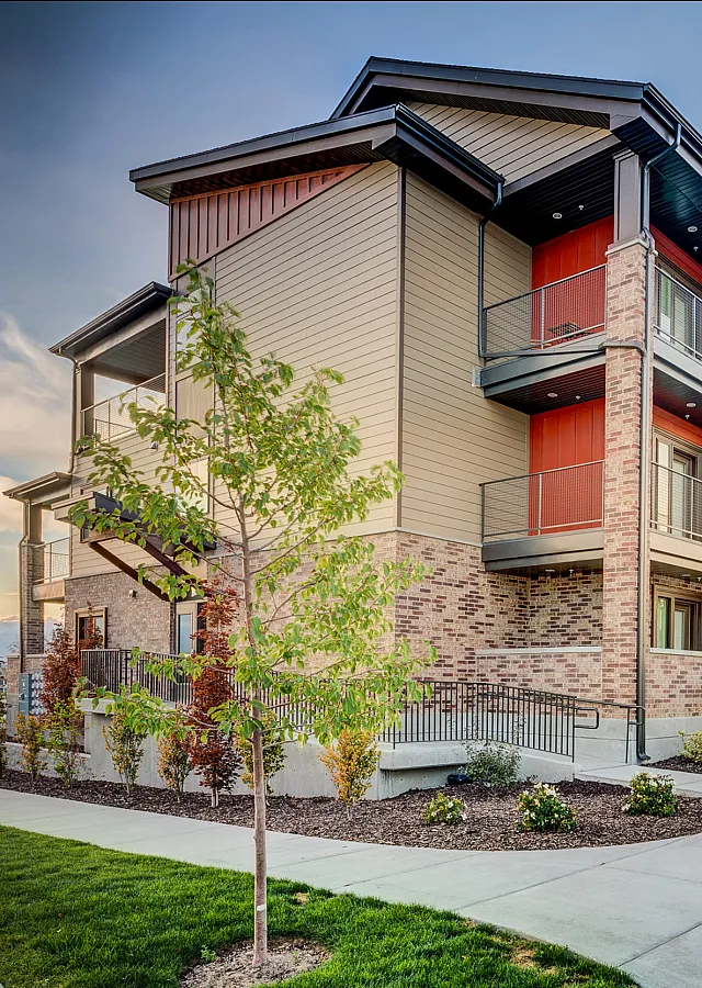 Contemporary multi-level apartment building with elegant brick fa&ccedil;ade, private balconies, and lush landscaping.