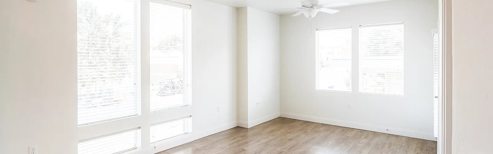 Bright and spacious living room with large windows and elegant wood flooring, offering ample natural light and a serene atmosphere.