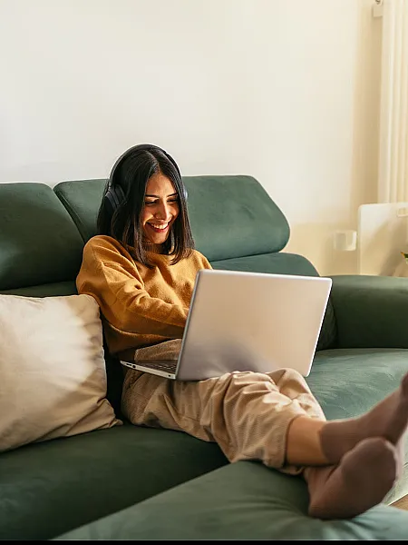 Bright and inviting living room featuring a cozy green sofa, perfect for relaxation and remote work, with lush plants adding a touch of freshness.