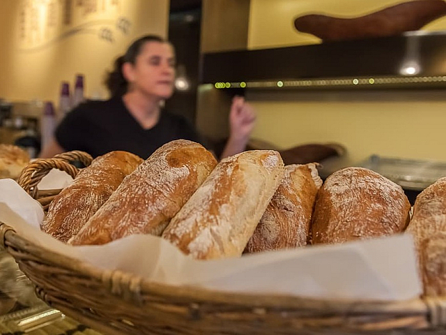 Inviting bakery display featuring fresh artisan breads in a woven basket, showcasing delicious crusts and golden hues.
