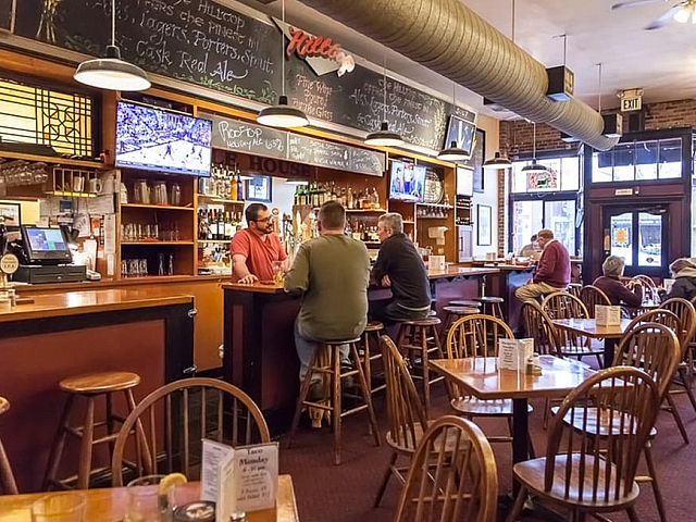 Cozy and inviting bar interior with warm wooden furniture, rustic decor, and patrons enjoying a relaxed atmosphere.