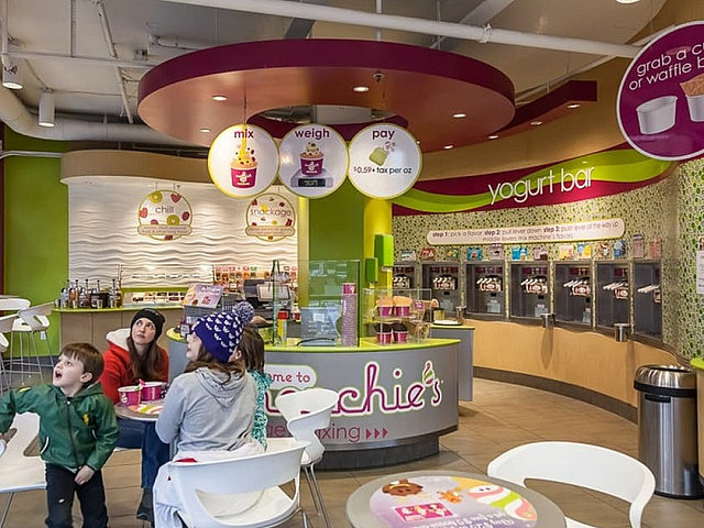 Modern frozen yogurt shop with vibrant decor, featuring a self-serve yogurt bar and family enjoying a cozy seating area.