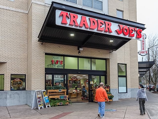 Charming Trader Joe's storefront with vibrant signage, inviting entryway, and people approaching the entrance, perfect for convenient grocery shopping.